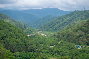 Naklejka na ściany i meble valley with a village in green deciduous mountains