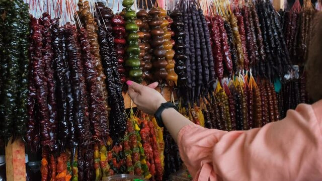Woman Choosing Georgian Sweets on Local Market. Buying Churchkhelas, Candle Shaped Grape Juice Candy with Nuts Inside. Travel, Tourism and People Concept