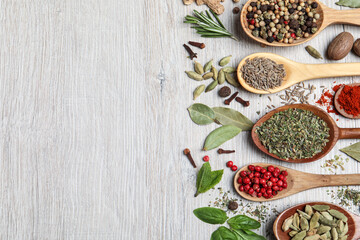 Different natural spices and herbs on light wooden table, flat lay. Space for text