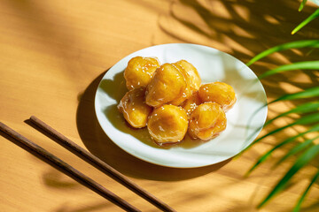 Fried bananas in caramel and batter with sesame seeds in a white plate. Chinese recipe and cuisine