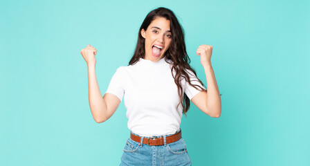 young pretty woman feeling happy, positive and successful, celebrating victory, achievements or...