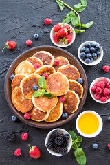 A healthy breakfast of cheese pancakes, berries, and honey. Creative atmospheric decoration