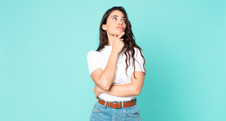 young pretty woman feeling thoughtful, wondering or imagining ideas, daydreaming and looking up to...