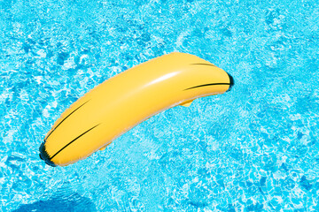 an inflatable banana on a background of swimming pool water. summer and travel concept. copy space - obrazy, fototapety, plakaty