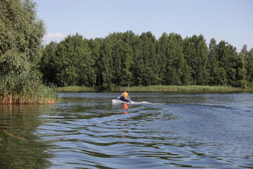 One inflatable motor boat with outboard motor fast floating on the water on green forest background...