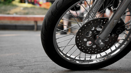 Motorcycle wheel close-up on a blurred background. Wheel on asphalt - summer day