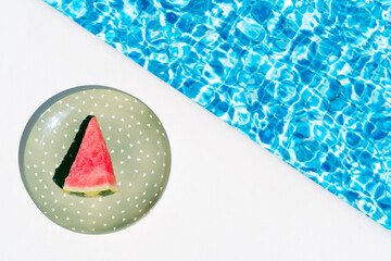 A slice of watermelon on a green plate by the pool. concept of summer, holidays and food