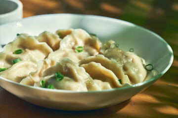 Classic Chinese boiled dumplings with meat and spicy soy sauce in a white plate. Chinese cuisine