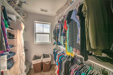 Full small walk in closet with window and laundry baskets