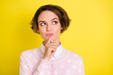 Photo of young attractive girl serious think minded idea hand touch chin look empty space isolated over yellow color background