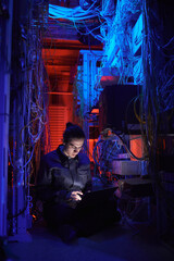 Vertical portrait of young technician setting up internet network in server room