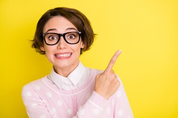 Photo portrait amazed funny girl in glasses pointing finger empty space isolated vibrant yellow...