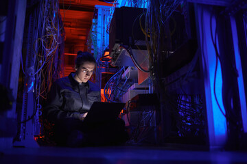 Portrait of young technician setting up internet network in server room, copy space