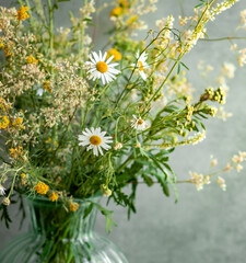 Bouquet of fresh wildflowers in a glass vase on a sunny summer morning