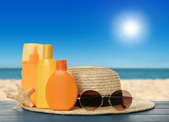 Different bottles of skin sun protection products and beach accessories on blue wooden table...