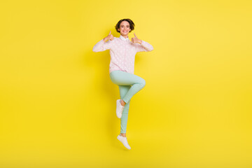 Fototapeta na wymiar Full length body size photo of cheerful model jumping showing thumb-up like sign smiling isolated vivid yellow color background