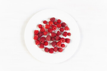 Ripe red raspberries on white plate