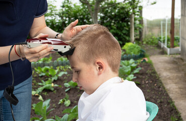 boy haircut with clipper in countryside