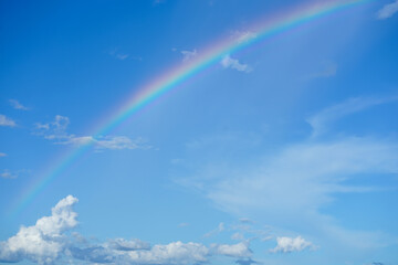 Fototapeta na wymiar clear blue sky with cloudscape and rainbow crossing the sky