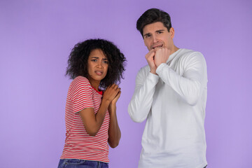 Frightened interracial couple afraid of something and looks into camera with big eyes full of...