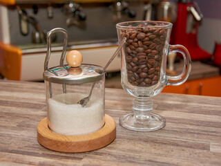 Glass bottles with cereals, crispy dice breads, chocolate chips, flour and icing sugar in a row on wooden table in kitchen or pantry for topping or ingredients of dessert or breakfast