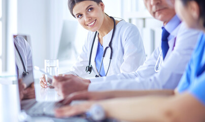 Smiling doctor using a laptop working with her colleagues in a bright hospital room