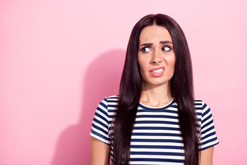 Photo of unhappy sad disgusted young woman look empty space make face grimace isolated on pink...