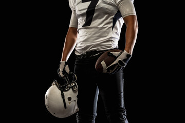 Cropped image of male American football player, athlete posing isolated on black studio background....