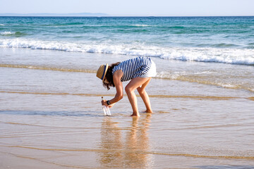 Botella de cristal con mensaje dentro enterrada en orilla de playa con el mar de fondo y olas