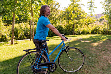 Naklejka premium Man walking in the park with his bicycle