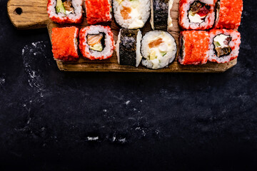 Sushi maki set served on wooden tablet shooting closeup from above. Japanese asian roll food composition with prepared rice and seafood following traditions