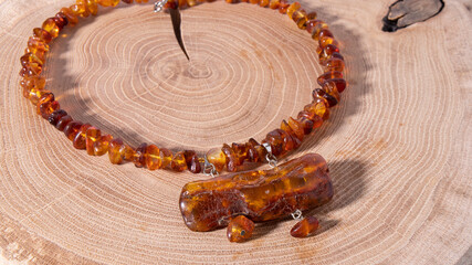 Orange Baltic amber necklace close up on a light wooden surface. Isolated handmade amber jewelry....