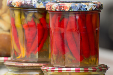Pickled hot peppers in glass jars. Canning vegetables in the fall. Preserved food.
