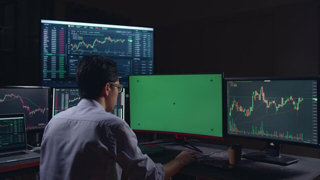 Stock Market Trader Working On A Computer With Isolated Mock-Up Green Screen And Analyzing Graphs On Multiple Computer Screens 
