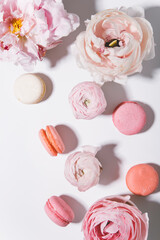 top view of beautiful pink peonies and macaroons on light background