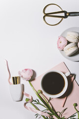 cup of coffee, pink flowers, perfume and macaroons on white background, top view
