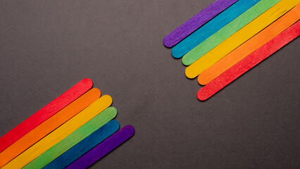 wooden sticks with the LGBT rainbow flag on both sides of the image on a black background