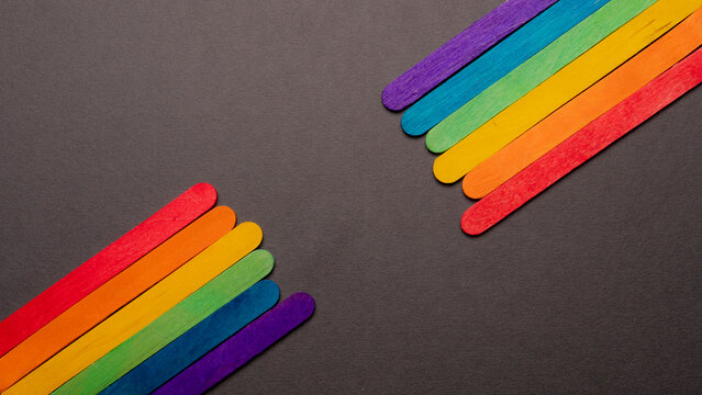 wooden sticks with the LGBT rainbow flag on both sides of the image on a black background