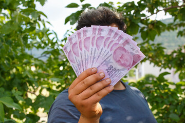 Young successful man holding Turkish lira banknotes.