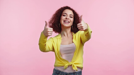 young happy woman showing thumbs up isolated on pink
