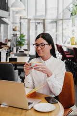 Businesswoman sitting in coffee shop and working on laptop.