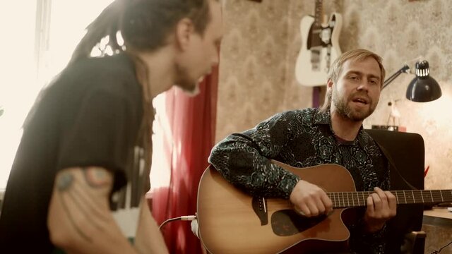 Man playing guitar and singing near friend