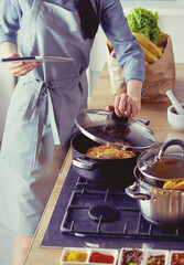 Young woman using a tablet computer to cook in her kitchen