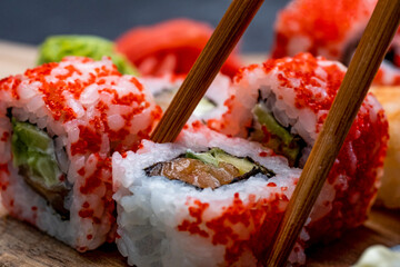 Closeup view on colorful set with sushi maki and wasabi. Person picks up traditional japanese roll...