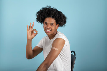 Successful Covid-19 vaccination. Vaccinated Latino man gesture okay and showing arm with a plaster after Vaccine injection.