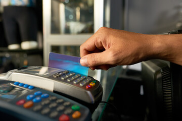 Hand of cashier swiping credit card with POS machine when accepting payment