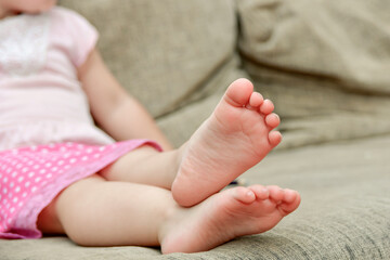 Baby feet of a child lying on the sofa.