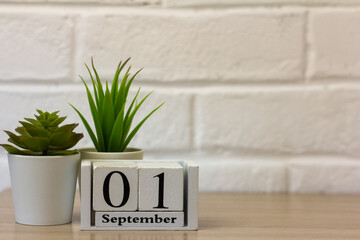September 1. Wooden calendar on a white brick background with an empty space. The concept of Back to school