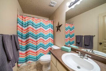 Bathroom interior with vanity sink and colorful zigzag patterned shower curtain