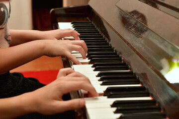 A girl and a guy play the piano in four hands. Rehearsal and training at a music school.